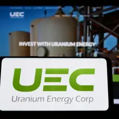 UEC Logo auf Smartphone. Hintergrund zeigt "Invest with Uranium Energy". Spannende uranium energy aktie prognose 2030?