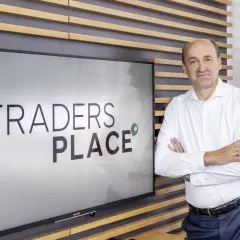 Mann steht vor Bildschirm mit "TRADERS PLACE" Schriftzug.