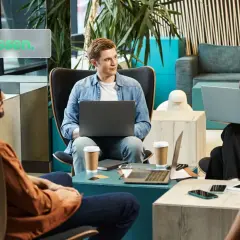 Menschen diskutieren über Finanzwissen, vielleicht über Amundi oder iShares, in einem modernen Büro mit Laptops und Kaffee.