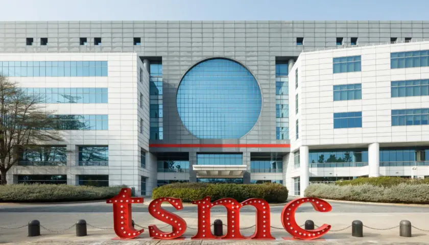 Große rote Buchstaben mit Lichtern bilden "tsmc" vor einem modernen Gebäude. Die TSMC Prognose 2030 wird hier visualisiert.