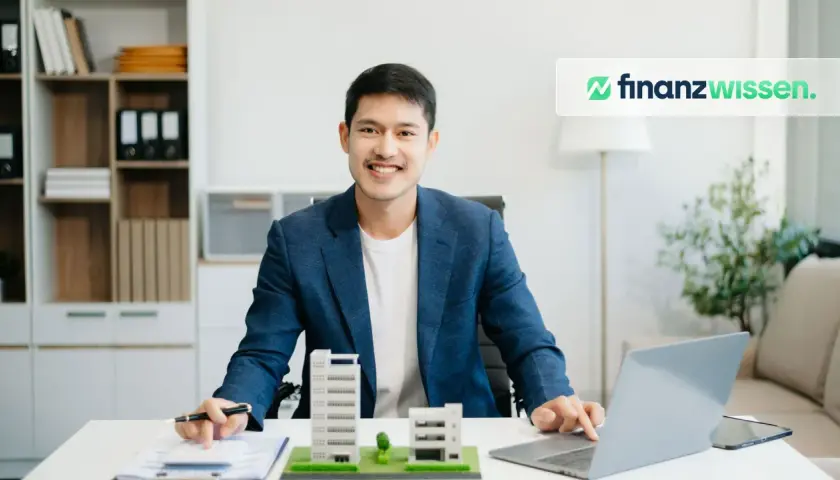 Ein Mann plant seine reits monatliche dividende mit Immobilienmodellen und einem Laptop.