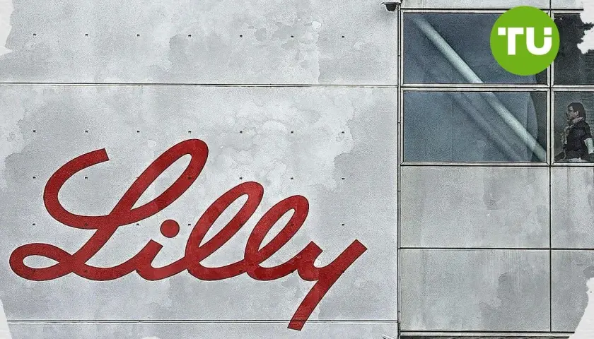 Großes rotes Lilly-Logo auf grauem Gebäude mit Fenstern und TU-Logo.