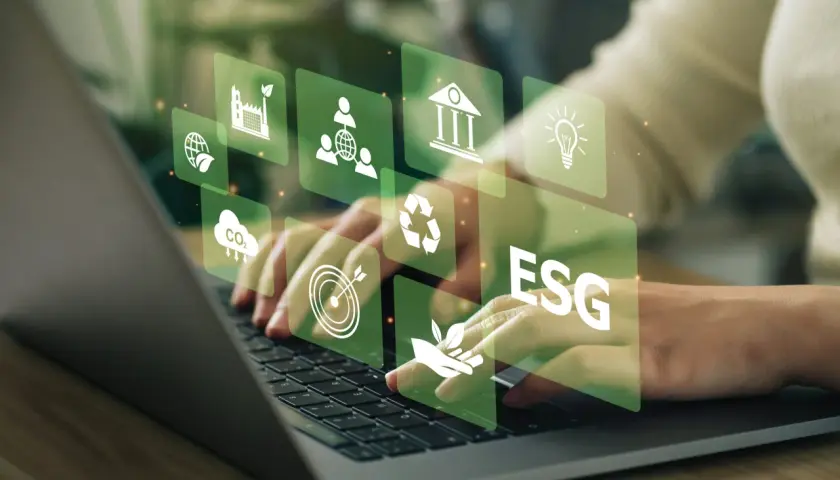 Hände tippen auf Laptop, überlagert von grünen Icons für Nachhaltigkeit und ESG-Kriterien. Investitionen in grüne energie aktien werden hier visualisiert.