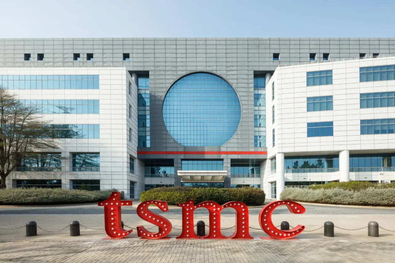 Große rote Buchstaben mit Lichtern bilden "tsmc" vor einem modernen Gebäude. Die TSMC Prognose 2030 wird hier visualisiert.
