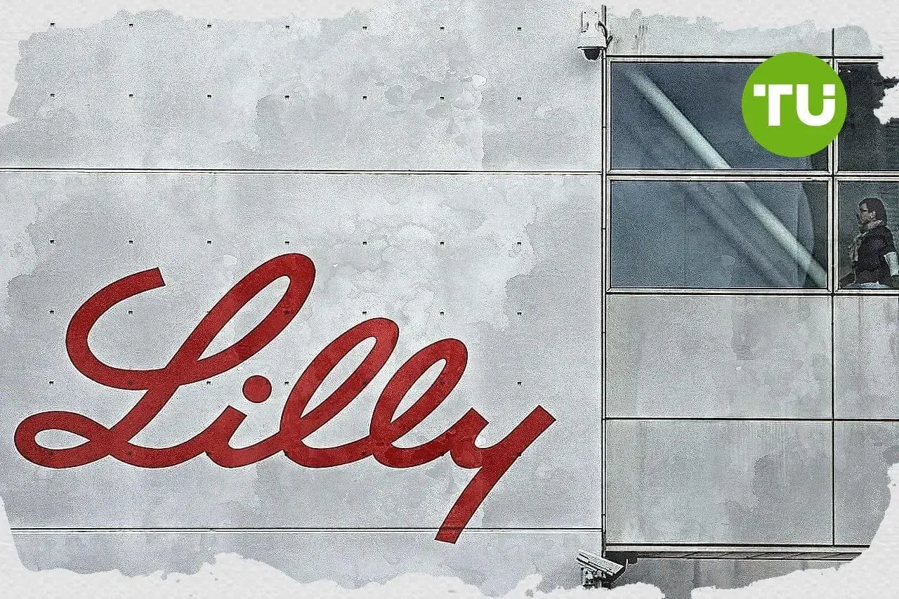 Großes rotes Lilly-Logo auf grauem Gebäude mit Fenstern und TU-Logo.