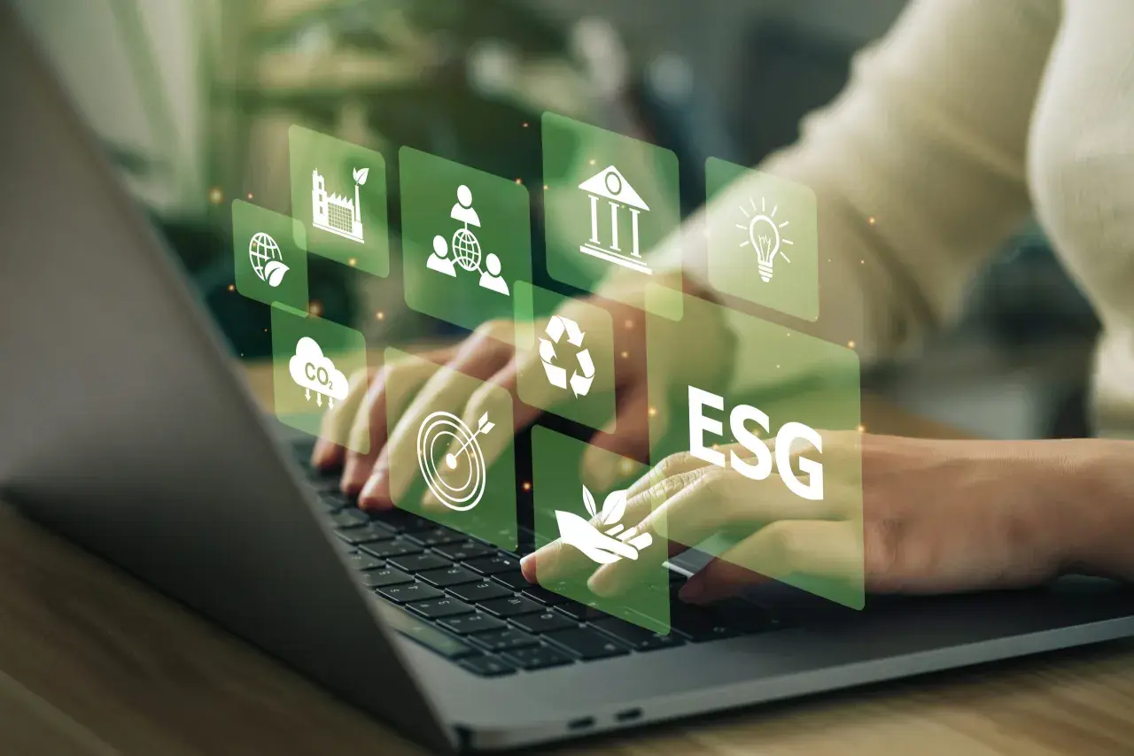 Hände tippen auf Laptop, überlagert von grünen Icons für Nachhaltigkeit und ESG-Kriterien. Investitionen in grüne energie aktien werden hier visualisiert.