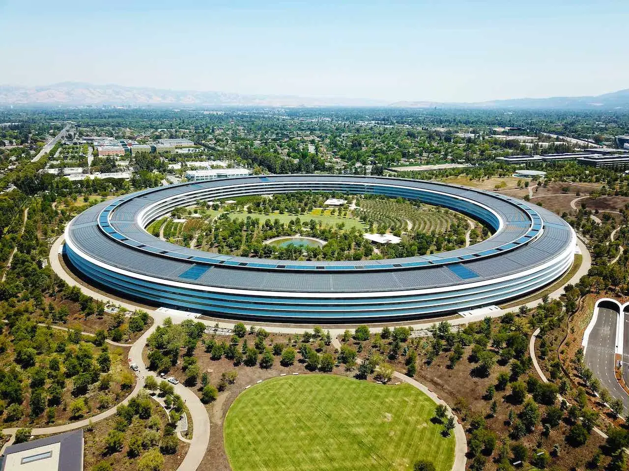 Das Apple Park Hauptquartier, ein Symbol für die reichsten Firmen der Welt, umgeben von Grünflächen und kalifornischer Landschaft.