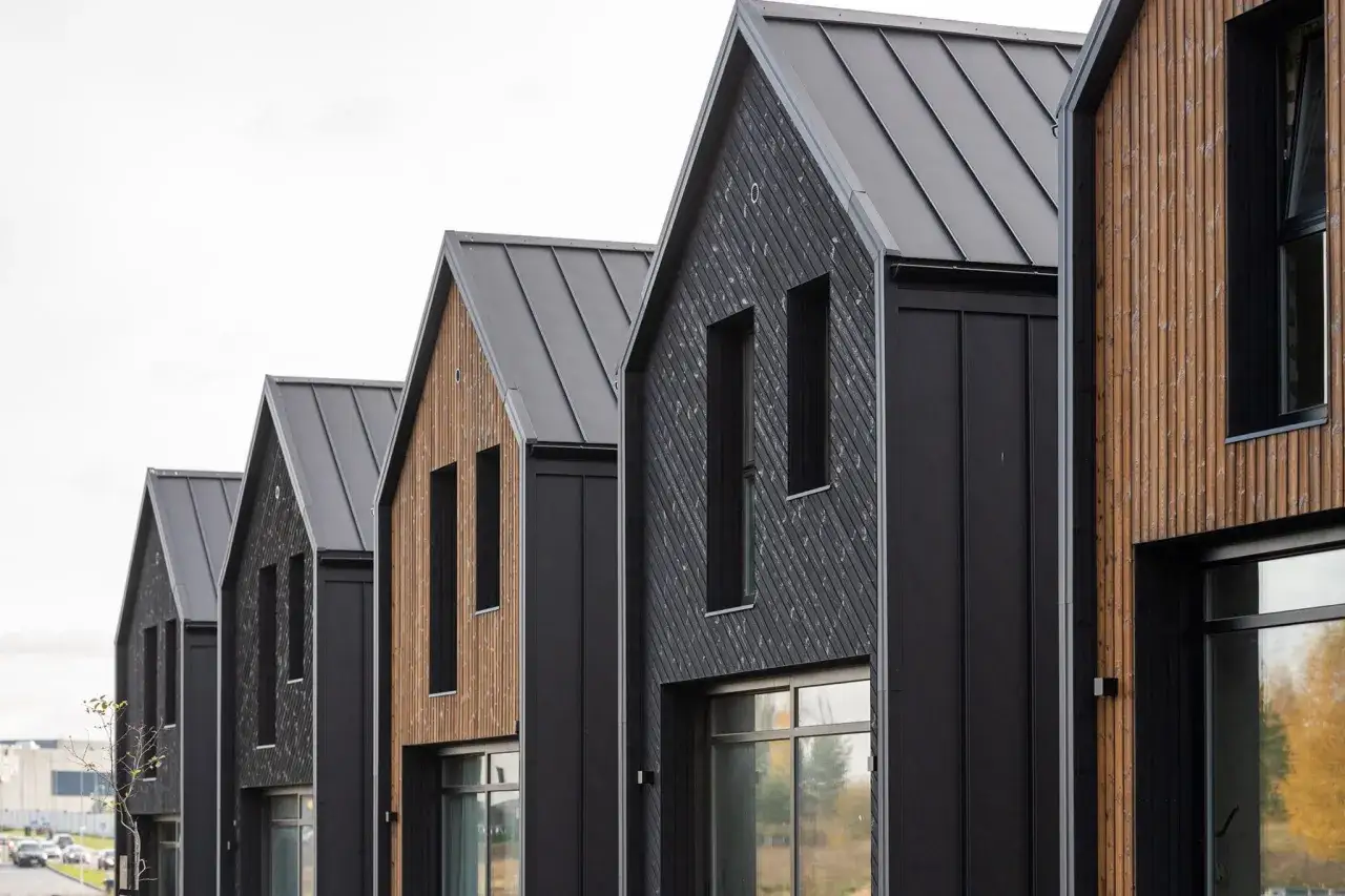 Moderne Reihenh&auml;user mit dunkler Fassade und Holzverkleidung. Gute estateguru erfahrungen sind hier sicher, wenn man in solche Objekte investiert.