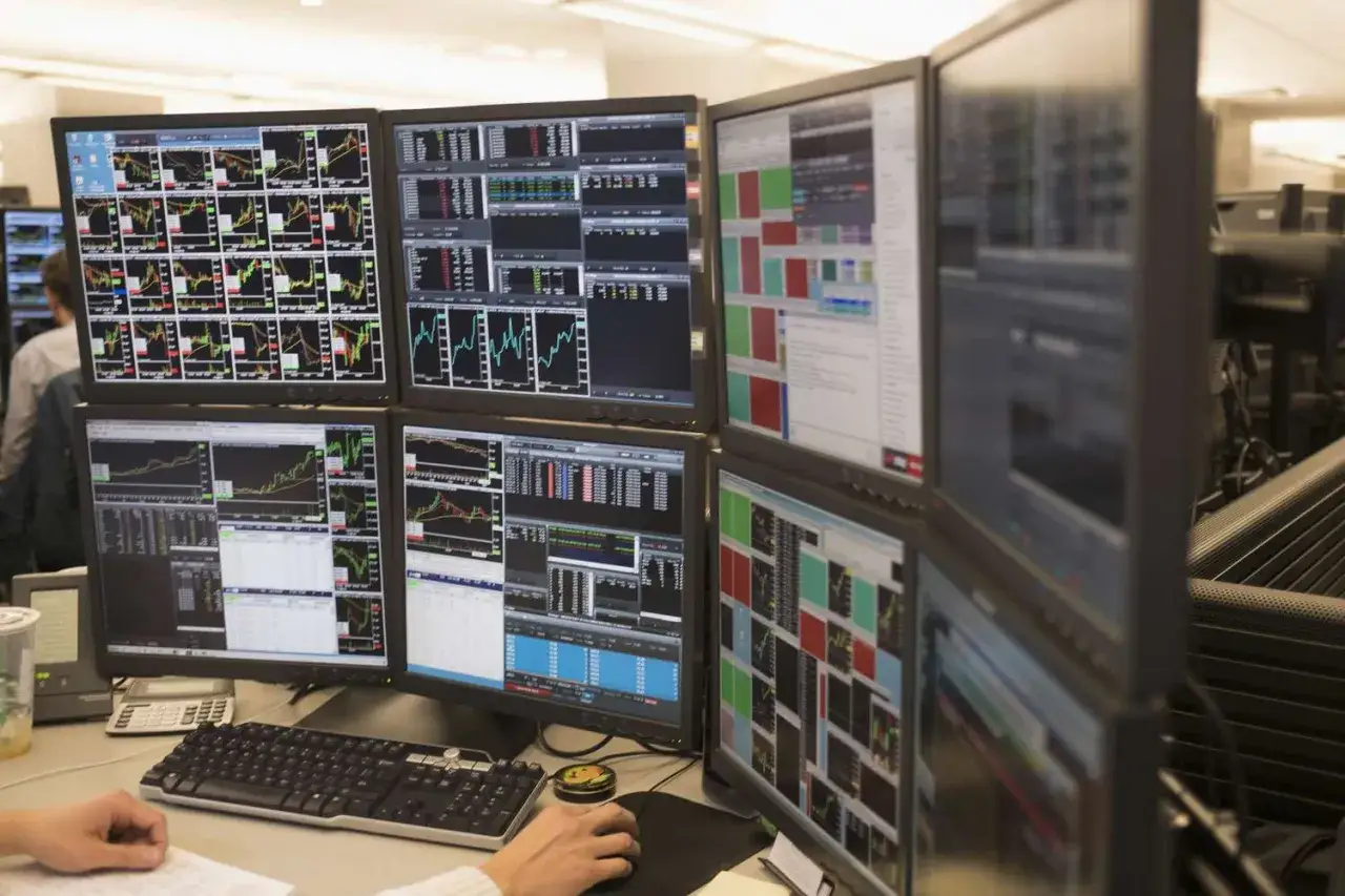 Mehrere Monitore zeigen B&ouml;rsencharts und Daten. Hier kann man sehen, wie man Daytrading lernen kann, um erfolgreich zu sein.