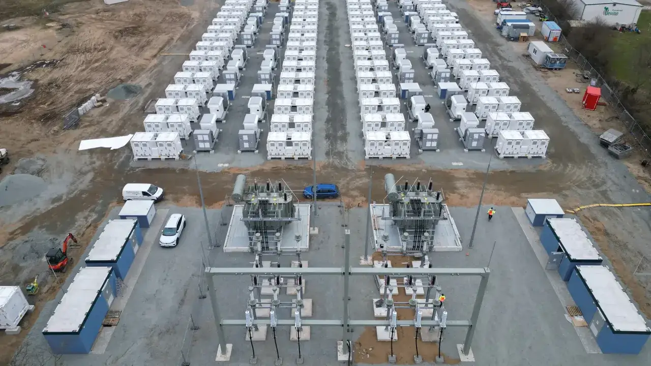 Gro&szlig;e Batterie-Speicheranlage mit vielen wei&szlig;en Containern, die an eine Stromversorgung angeschlossen sind. Ein Blick auf die Zukunft der Energiespeicherung, die auch f&uuml;r Investoren in Batteriespeicher Aktien interessant ist.